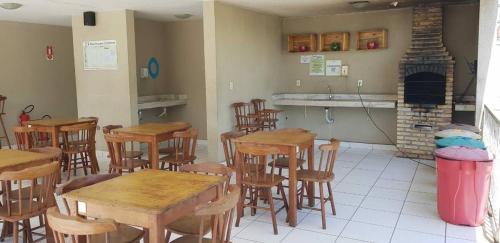a restaurant with wooden tables and chairs and a fireplace at Apartamento Compacto Mobiliado in Natal