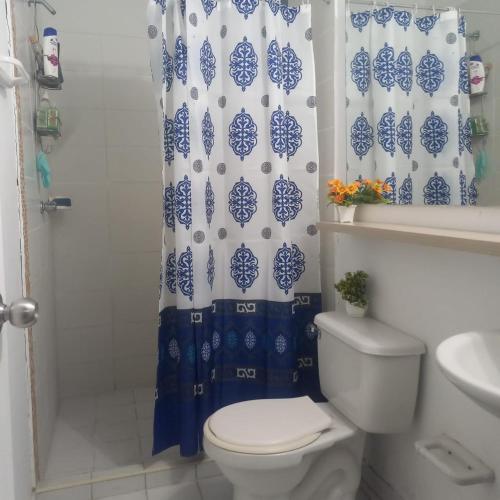 a bathroom with a toilet and a blue and white shower curtain at Habitación en Valledupar in Valledupar