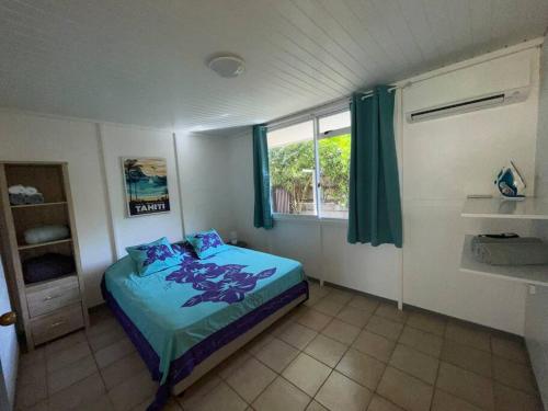 Schlafzimmer mit einem Bett mit blauer Bettwäsche und einem Fenster in der Unterkunft Tuatahi Beach Lodge in Punaauia