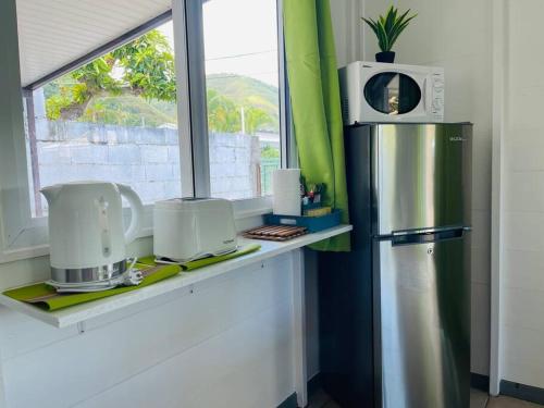 a kitchen with a counter with a refrigerator and a window at Tuatahi Beach Lodge in Punaauia
