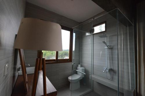 a bathroom with a toilet and a glass shower at Ohmmstay - Rumah Pendopo in Tanjungtirto