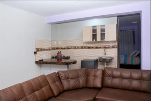 sala de estar con sofá marrón y cocina en TRANSFER VIP HOSTEL, en Lima