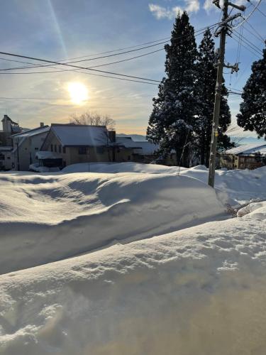 長野的住宿－Elan Lodge Akakura，一条有雪覆盖的街道,在后面有太阳