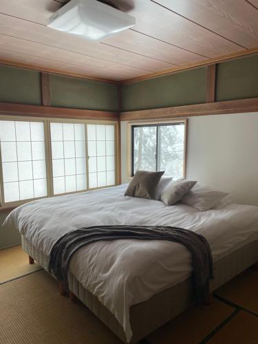 a bedroom with a large bed in a room with windows at Elan Lodge Akakura in Nagano