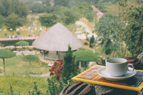 a cup of coffee sitting on a plate on a table at Thung Nham Resort in Ninh Binh
