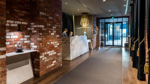 um lobby com uma parede de tijolos e duas pessoas num balcão em Free Parking-Luxurious & Spacious Skyline view Apt em Melbourne