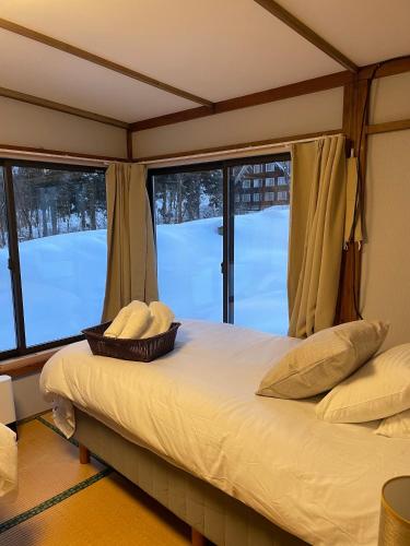 a bedroom with a bed with two pillows and windows at Elan Lodge Akakura in Nagano