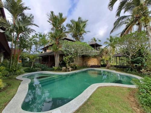 una piscina frente a una casa con palmeras en Dzawani Villa Ubud, en Tampaksiring