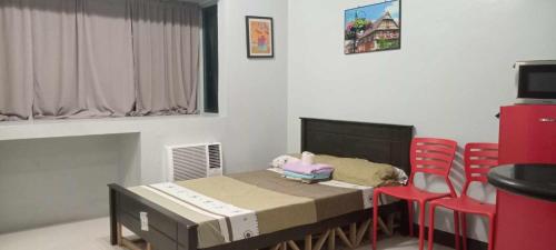 Habitación con 1 cama y 2 sillas rojas en Place to stay en Manila