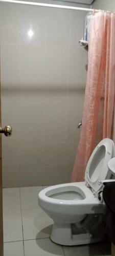 a bathroom with a white toilet and a pink shower curtain at Place to stay in Manila