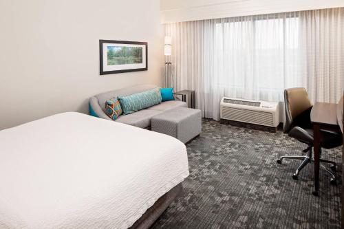 a hotel room with a bed and a couch at Courtyard by Marriott Houma in Houma