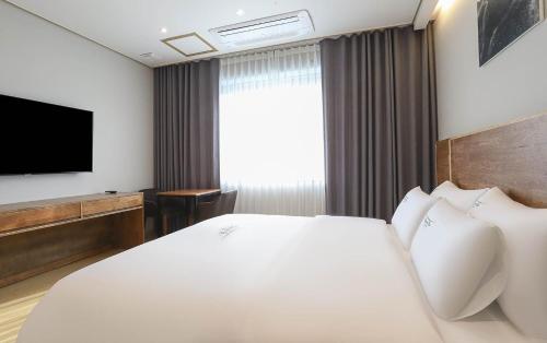 a hotel room with a bed and a flat screen tv at Hotel Grand Bay Boryeong in Boryeong