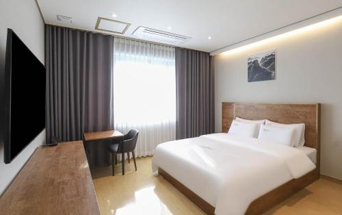 a bedroom with a bed and a desk and a window at Hotel Grand Bay Boryeong in Boryeong