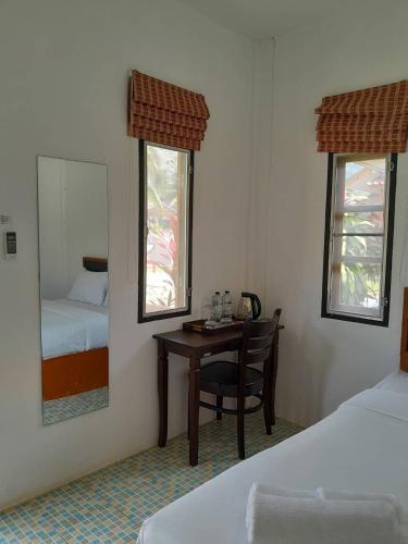 a bedroom with a desk and a bed and a mirror at Khaolak Banana Bungalow in Khao Lak
