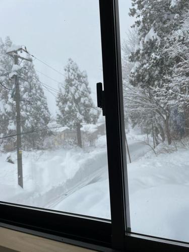 a view from a window of a snow covered yard at Elan Lodge Akakura in Nagano