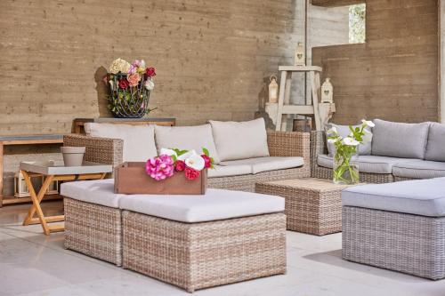 a patio with wicker chairs and couches and flowers at CallaLillyJardin in Malcesine
