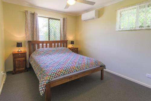 um quarto com uma cama e uma janela em Hibiscus Holiday Home em Urangan