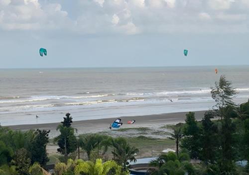 a beach with people flying kites in the ocean at Timurbay Seafront Residence & Suites in Kuantan