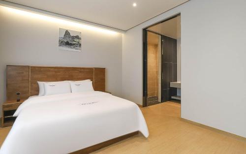 a bedroom with a large white bed and a mirror at Hotel Grand Bay Boryeong in Boryeong