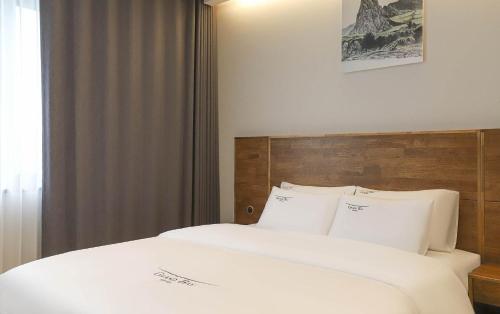 a bed with white sheets and a wooden headboard at Hotel Grand Bay Boryeong in Boryeong