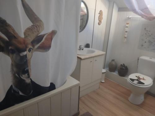 une salle de bains avec une tête de cerf sur le mur dans l'établissement Les quatre vents, à Ars