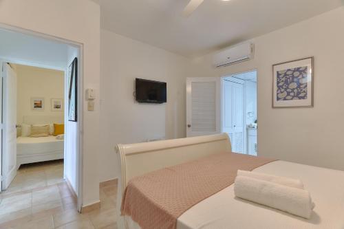 a white bedroom with a bed and a television at New! Lovely And Spacious Fully Equipped Condo In Cap Cana in Punta Cana