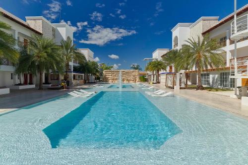 a large swimming pool with chaise lounge chairs and palm trees at New! Lovely And Spacious Fully Equipped Condo In Cap Cana in Punta Cana