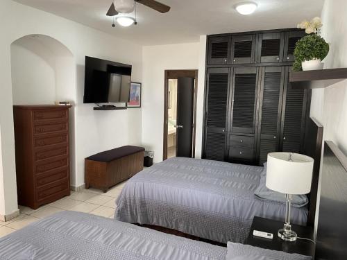een slaapkamer met een bed, een dressoir en een televisie bij Casa Mel, Excelente ubicacion, seguridad in Cozumel