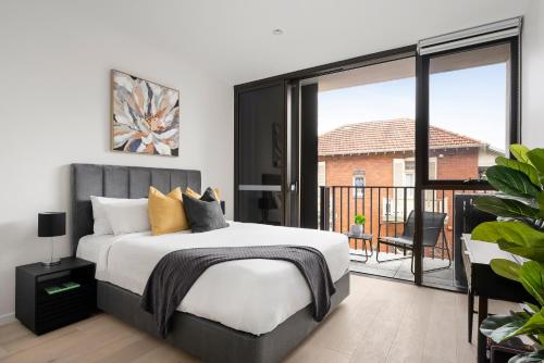 1 dormitorio con 1 cama grande y balcón en Urban Rest North Sydney Apartments en Sídney