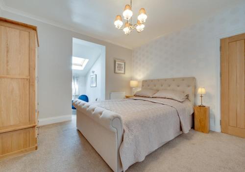 a bedroom with a large bed and a chandelier at Home Croft in Tenby