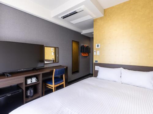 a hotel room with a bed and a flat screen tv at Hotel Wing International Shizuoka in Shizuoka