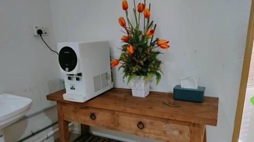 ein Tisch mit einer Mikrowelle und einer Vase mit Blumen in der Unterkunft Homestay Roma Suite in Kuala Terengganu