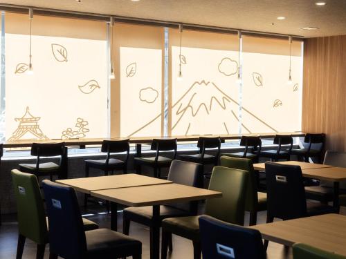 a dining room with tables and chairs and a large screen at Hotel Wing International Shizuoka in Shizuoka
