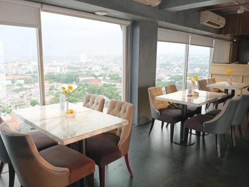 a restaurant with tables and chairs and large windows at Channel Stay Warhol Simpang Lima Semarang in Semarang