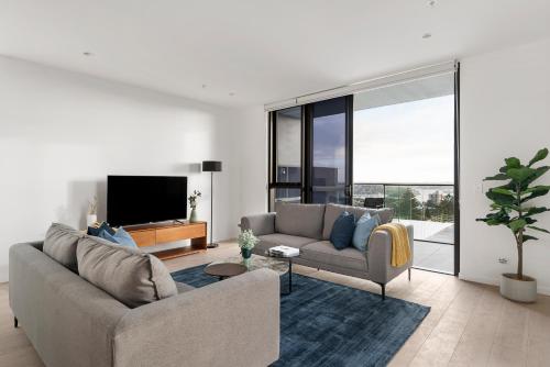 a living room with a couch and a tv at Urban Rest North Sydney Apartments in Sydney