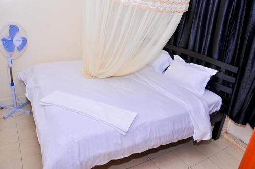 1 dormitorio con 1 cama blanca con dosel en Milany Homes - NEAR JKIA AIRPORT en Nairobi