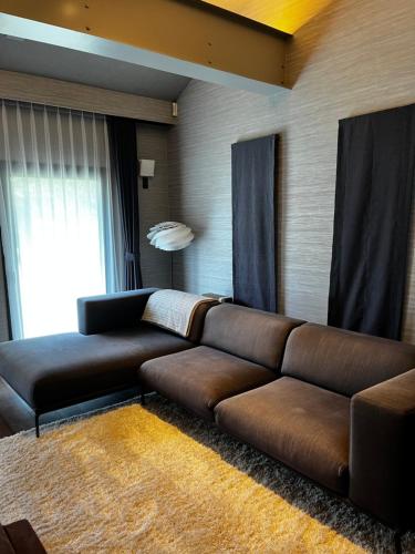 a living room with a brown couch and a window at 椿邸・TSUBAKI-Tei in Jozankei