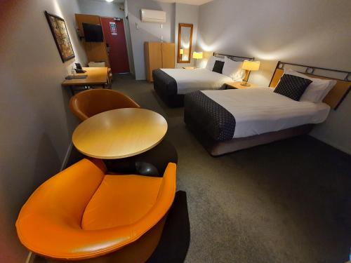 a hotel room with two beds and a couch and a table at Off Broadway Motel in Auckland