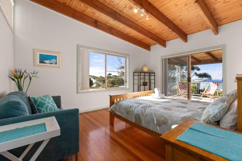 a bedroom with a bed and a couch at Absolute Blue by Experience Jervis Bay in Hyams Beach