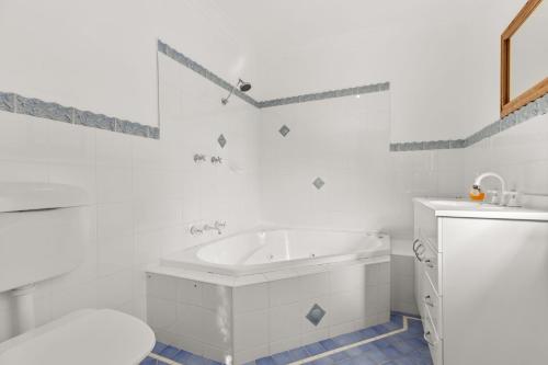 a white bathroom with a tub and a sink at Absolute Blue by Experience Jervis Bay in Hyams Beach