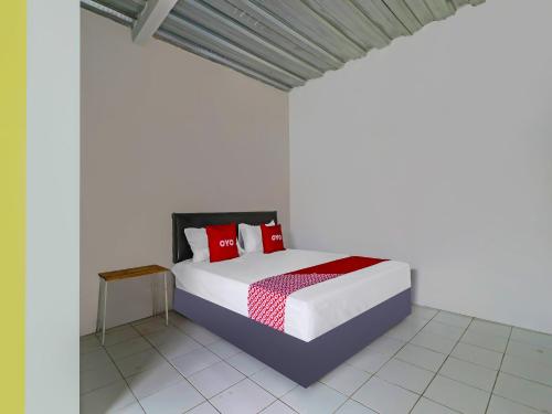 een slaapkamer met een bed met rode kussens erop bij OYO 90809 Homestay Black Pink Merah Jambu Syariah in Garut