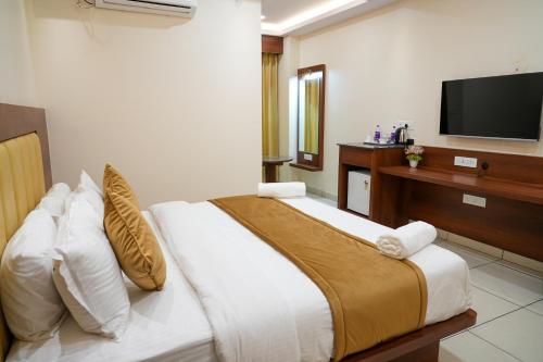 a bedroom with a bed with a tv on the wall at Sri Krishna Inn - Kempegowda Airport Bangalore in Bangalore