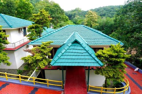 a house with a green roof and a red carpet at HOTEL MEENAKSHI in Kolattupuzha