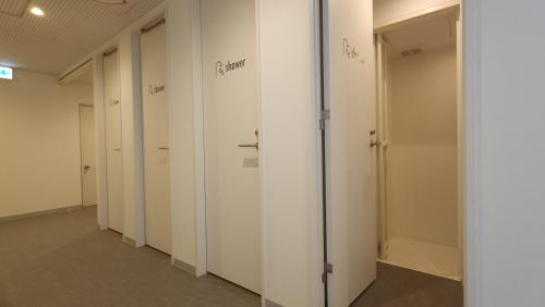 a row of white doors in a hallway at Acro Capsule Hotel Namba Dotonbori in Osaka