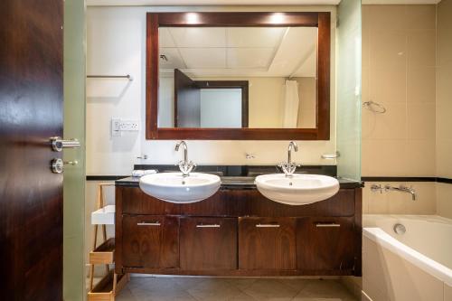 a bathroom with two sinks and a mirror at ALH Vacay - 2 bedrooms Apartment in Golf Towers 1 in Dubai