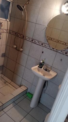 uma casa de banho com um lavatório e um chuveiro com um espelho. em Casa shoke em Rosarito