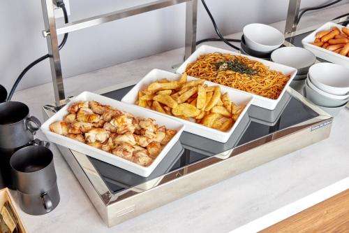 a buffet with three trays of food on a table at Travelodge Nagoya Sakae in Nagoya