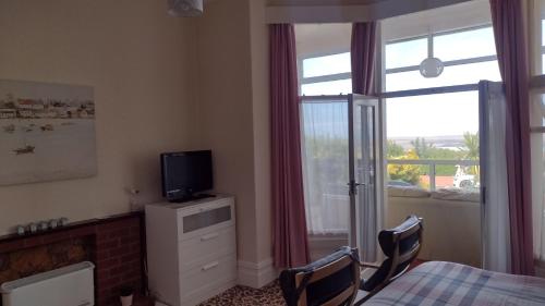 a bedroom with a bed and a television and a window at The Kathrene in Fleetwood