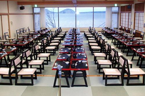 a row of tables and chairs in a room at Sapporo's Secret Onsen Sanctuary Marukoma Onsen Ryokan in Chitose
