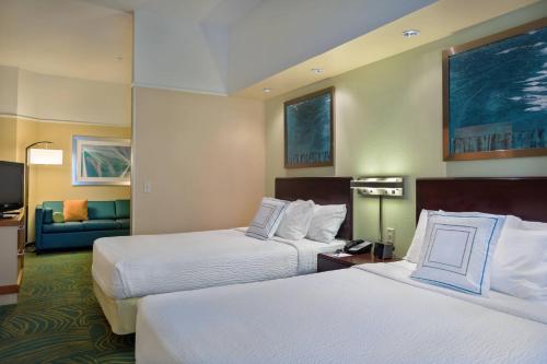 a hotel room with two beds and a couch at SpringHill Suites St Petersburg Clearwater in Clearwater